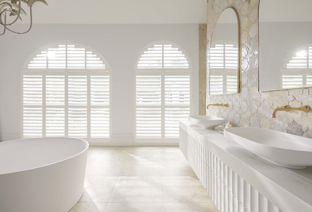 Arched windows, plantation shutters, bright bathroom